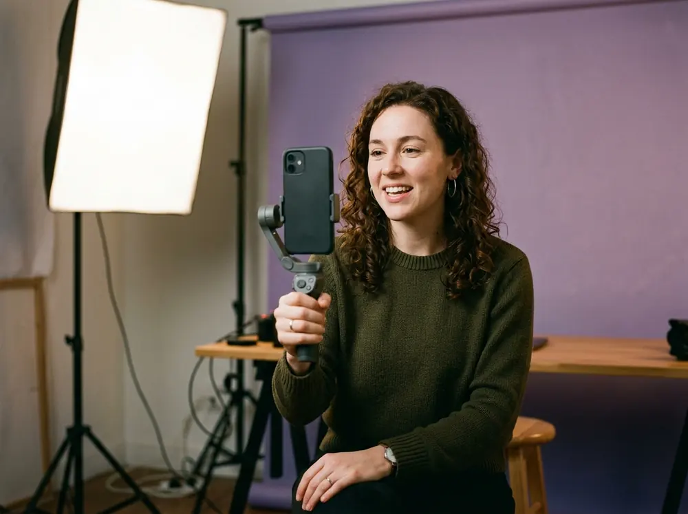 A social media manager films a vertical talking-head clip on a phone, the creator format a Captions review covers